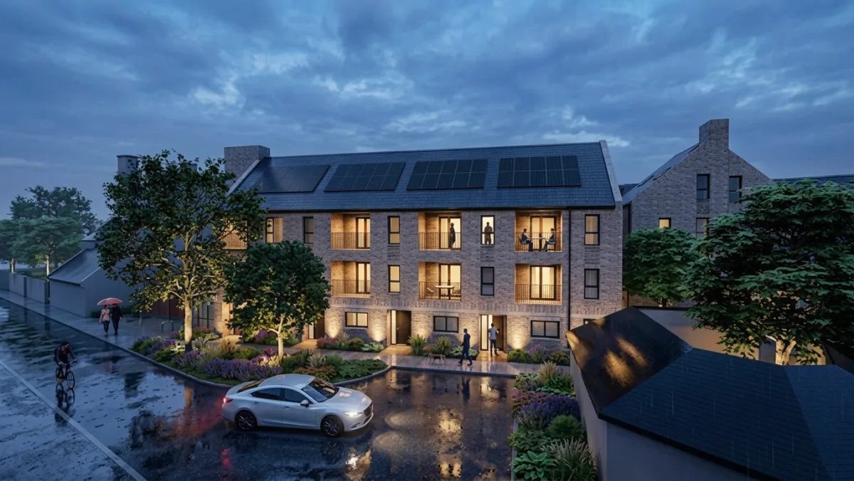 Computer-generated evening view of a three-storey brick block of flats with balconies, solar panels on the roof and planted front gardens, seen from the street.